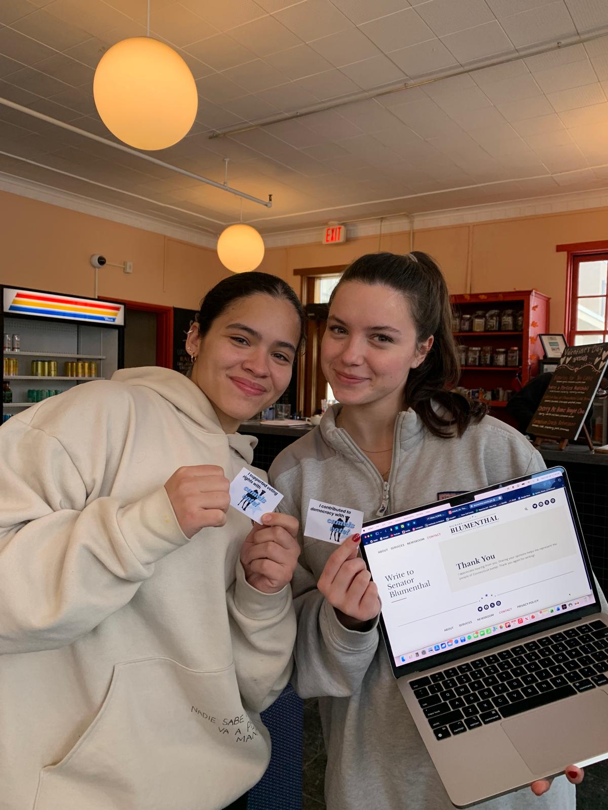 Two students hold Camels Vote “I contacted Senator Blumenthal” stickers next to a Thank You confirmation page on a laptop.